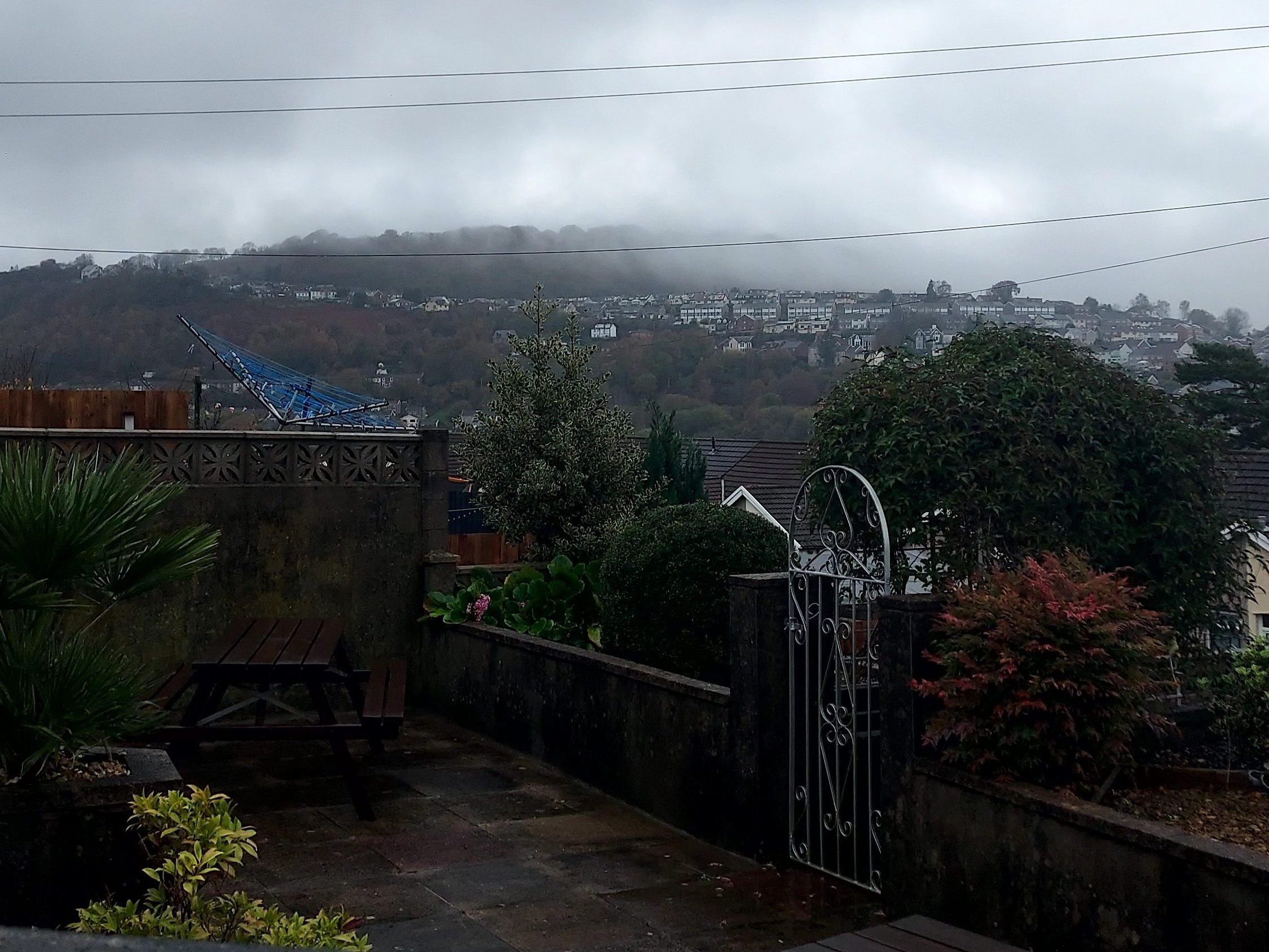 Back gardens with tilted washing line and low cloud over hills beyond