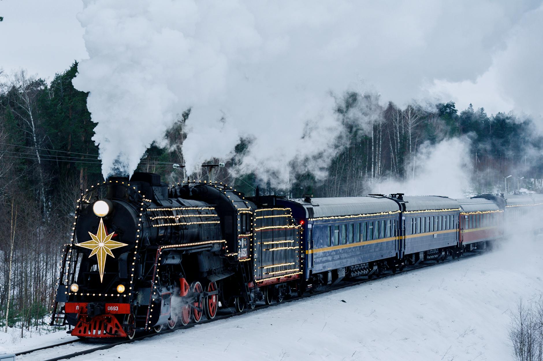 Christmas train with fairy lights through snowy landscape