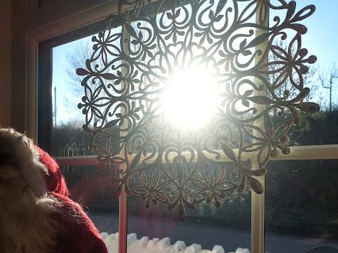 Winter sun shining through Christmas star decoration with santa's beard and hat visible in corner