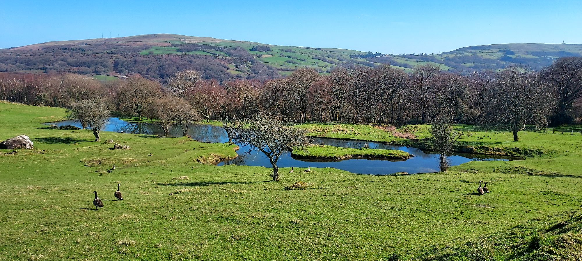 Idyllic lake on green hillside with mountain views beyond