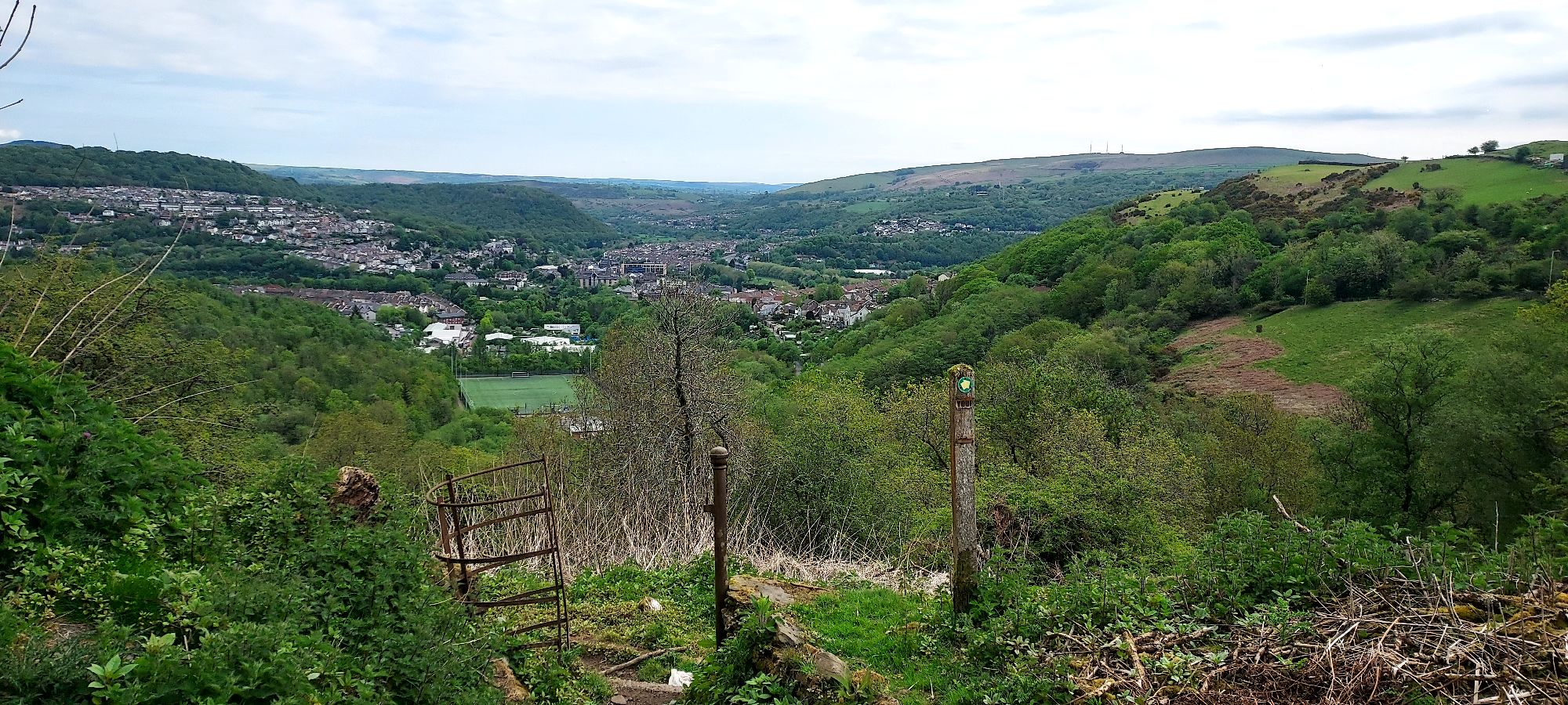 Hilltop view over welsh hills and valley with walking route signposted in foreground